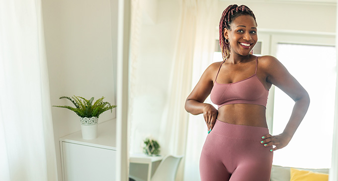 a happy lady looking at her figure in a mirror after her liposuction treatment